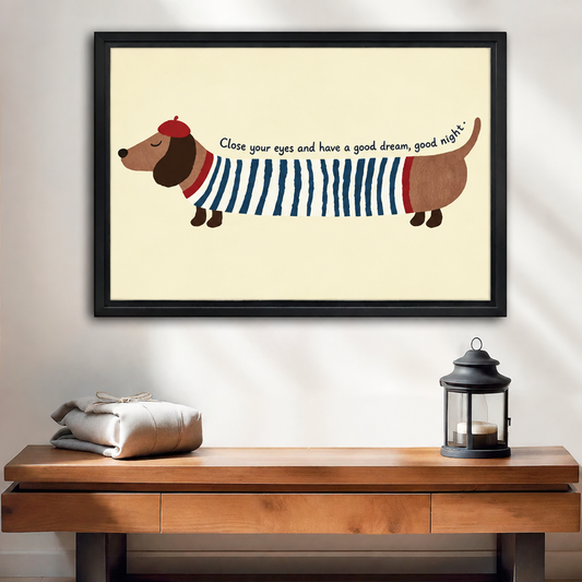 Black-framed whimsical dachshund wall art above a wooden console beside folded linens and a black candle lantern.