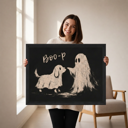 Smiling woman holding black-framed whimsical dog ghost canvas wall art with cream illustrations and playful Boo-p lettering.