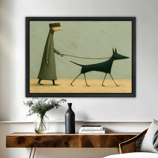 Whimsical framed wall art print of a robed figure walking a sleek black dog, displayed above a wooden console table