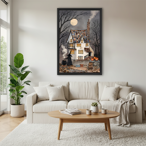 Framed folk-art haunted house wall art displays a crooked cottage, steaming chimney, bare branches, and glowing pumpkins.