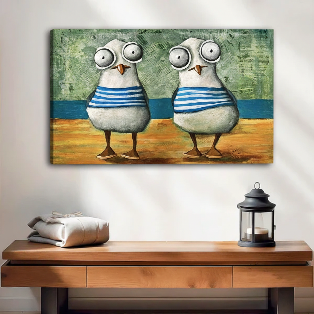 Unframed canvas print of two big-eyed seagulls in sailor stripes standing on a sandy beach, displayed above a rustic wooden sideboard