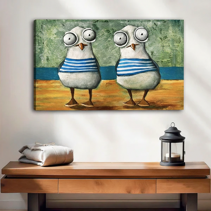 Unframed canvas print of two big-eyed seagulls in sailor stripes standing on a sandy beach, displayed above a rustic wooden sideboard