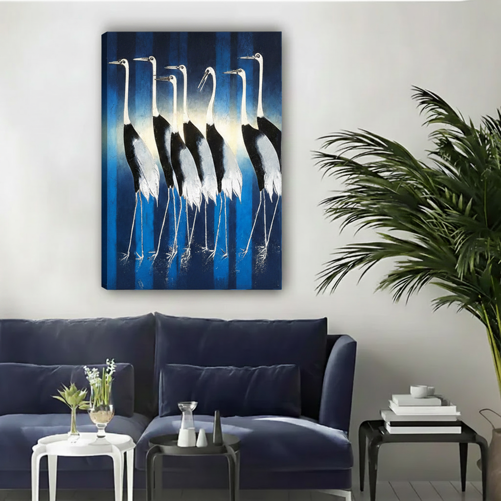 Dramatic gallery wrap canvas of white cranes with black wings bathed in a luminous blue glow, hung above a navy sofa alongside a large indoor palm plant
