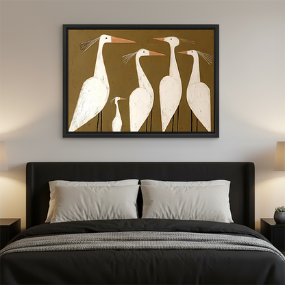 Black-framed white egrets canvas wall art with an olive-brown background displayed above a black table with plants.