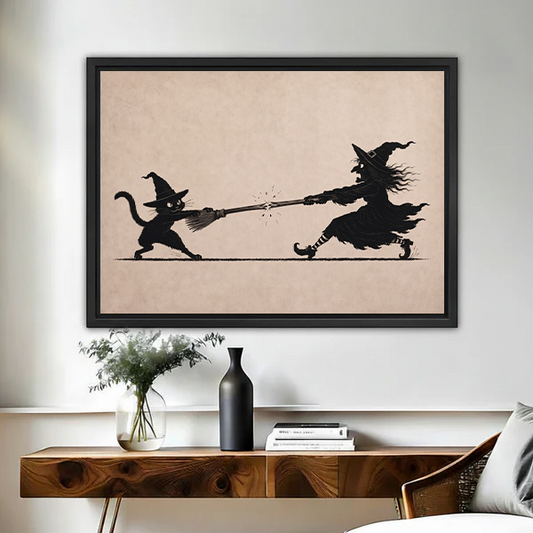 Framed witch and black cat broom tug of war canvas wall art above a wood console with vase and flowers