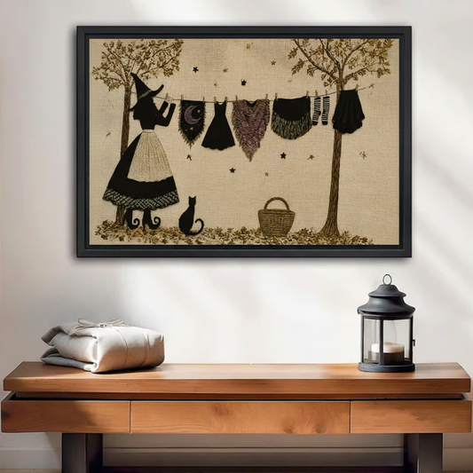 Framed witch and black cat canvas wall art above a console with folded linens and lantern
