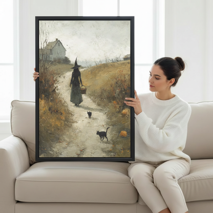 Woman holding large witch walking autumn path with two black cats and pumpkins vintage oil painting framed canvas print, cottagecore wall art size reference lifestyle photo on cream sofa