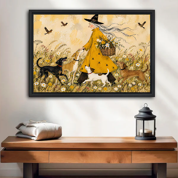 Framed whimsical witch and dogs canvas wall art with meadow flowers above a wooden console and lantern.