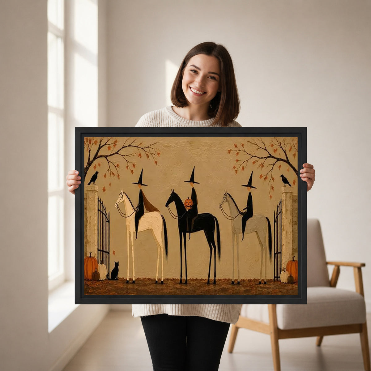 Woman holding framed witches on horses canvas wall art featuring three riders, autumn branches, pumpkins, and a black cat