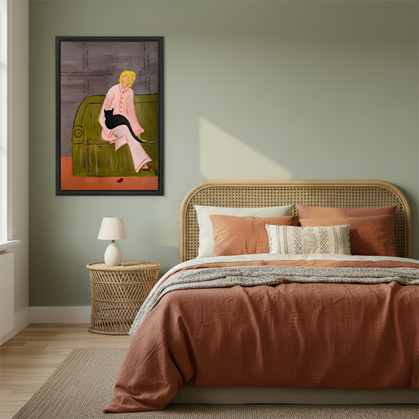 Woman holding framed woman with black cat canvas wall art featuring a pink outfit and an olive-green sofa.