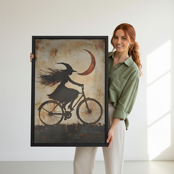 Woman holding framed gothic witch bicycle canvas wall art beneath a crescent moon in a bright room