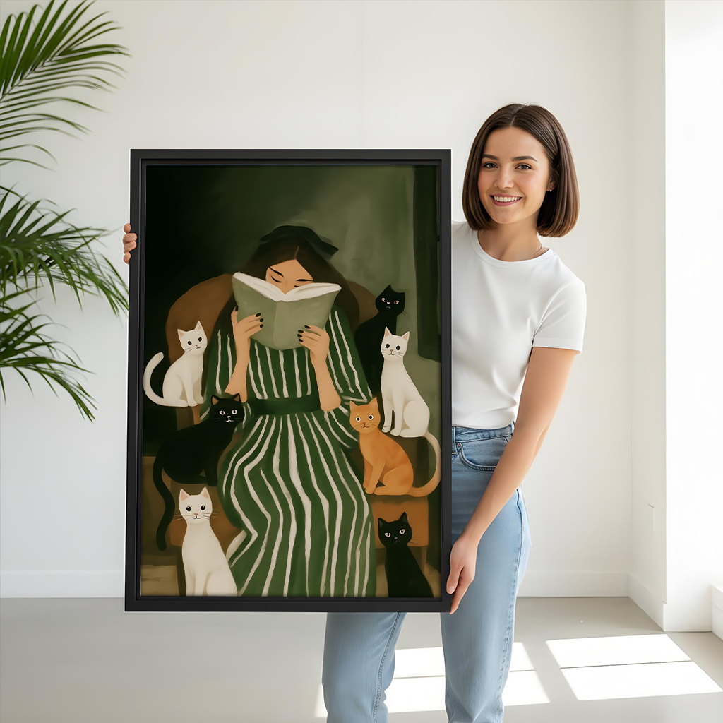 Woman reading with cats canvas wall art held by a smiling woman, showing the framed artwork's scale
